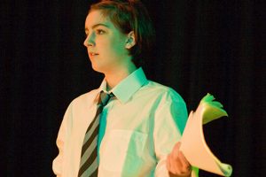 A teenage girl on stage holding a script